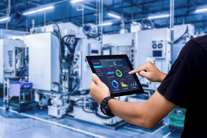 Smart industry control concept.Hands holding tablet on blurred automation machine as background